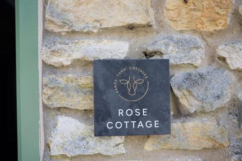 a sign on a stone wall with the name of a rosie coffeeastery at Rose Cottage - Sands Farm in Wilton