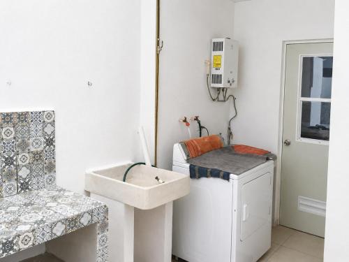 a bathroom with a sink and a washing machine at CasaMEXH Veredas - Tu refugio familiar entre la selva, cenotes y la playa, vive tus vacaciones lejos del turismo masivo, a 10 Min de la ruta de los cenotes y el arrecife más cercano de la Riviera Maya - A 20 min de Cancún y Playa del Carmen in Puerto Morelos