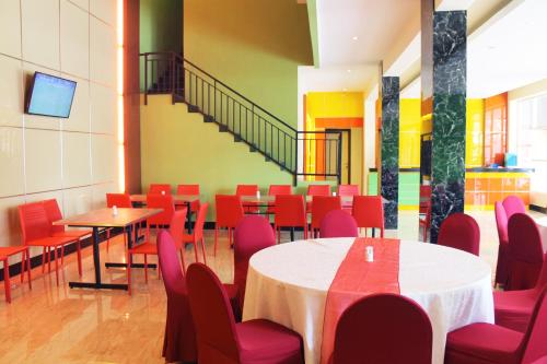 Maleosan Inn Manado Hotel في مانادو: غرفة طعام مع طاولات وكراسي حمراء