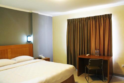 Tempat tidur dalam kamar di Maleosan Inn Manado Hotel