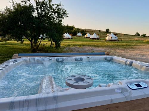 a hot tub in a field with tents in the background at Glamping Stolat in Stolat