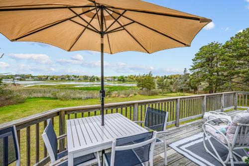 a table and chairs on a deck with an umbrella at Waterfront Escape with Stunning Views on Bass River in West Dennis