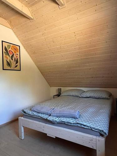 a bed in a room with a wooden ceiling at Za Bocianami- domki w Bartoszymlesie in Stara Kiszewa