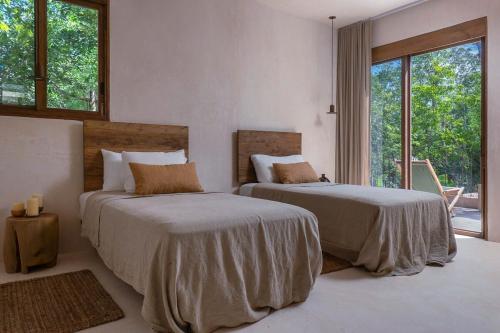 a bedroom with two beds and a large window at 3BR Home in Gated Community with Private Rooftop Plunge Pool, Grill & Shared Pool in Tulum