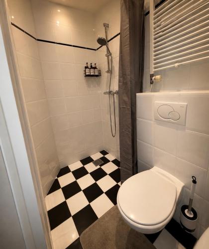 a bathroom with a toilet and a black and white checkered floor at Manor Suite Amsterdam in Amsterdam