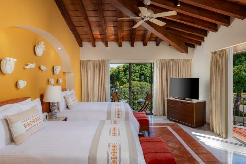 a bedroom with a large bed and a tv at Casa Velas Adults Only All Inclusive in Puerto Vallarta