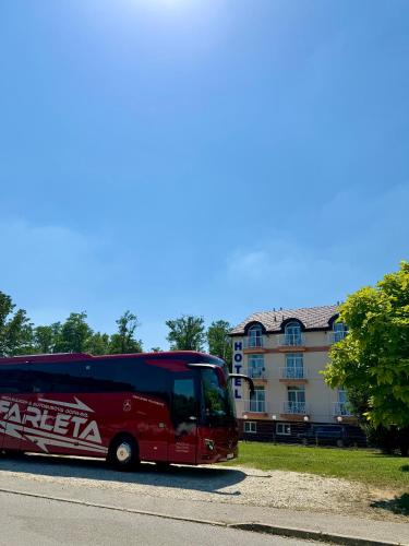 a red bus parked in front of a building at Hotel Imperium in Moravske-Toplice