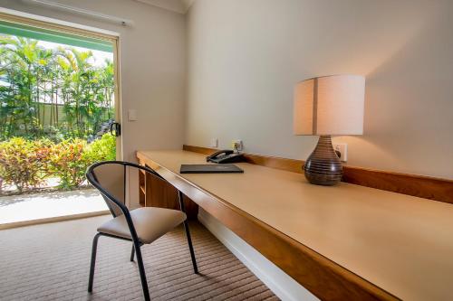ein Büro mit einem Schreibtisch mit einer Lampe und einem Stuhl in der Unterkunft Shamrock Gardens Motel in Mackay