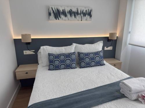 a bedroom with a bed with blue and white pillows at Alojamientos Dima Costa in Laredo