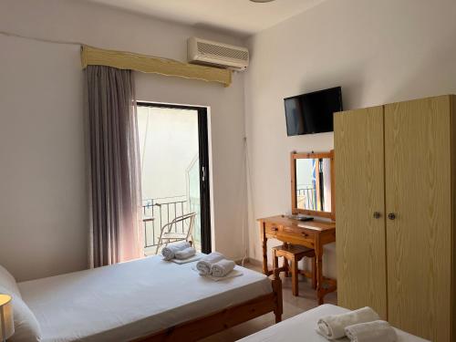 a bedroom with two beds and a window and a desk at Villa Xenia in Ammoudia