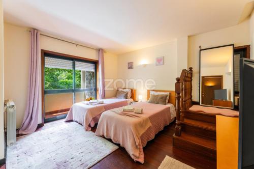 a bedroom with two beds and a large window at Casa da Lagoa II in Terras de Bouro