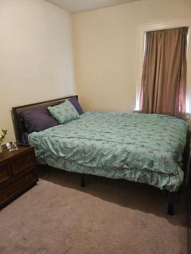 a bedroom with a bed with a green comforter and a window at Plantlife LLC Lodge U room in Minneapolis