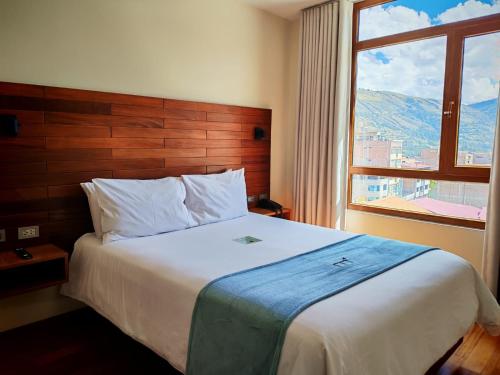 a bed in a hotel room with a large window at Muña Hotel Andahuaylas in Andahuaylas