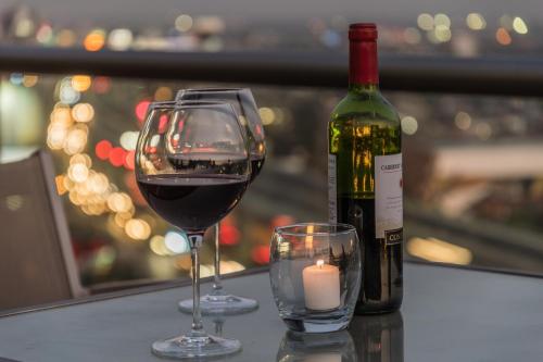 a glass of wine and a bottle of wine and a candle at Suites Perisur Apartamentos Amueblados in Mexico City