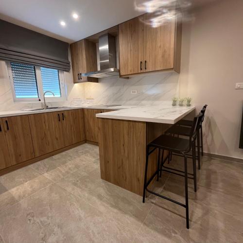 a kitchen with wooden cabinets and a table and chairs at Golden View Berat, 3BR Apartment with Castle View & Parking in Berat