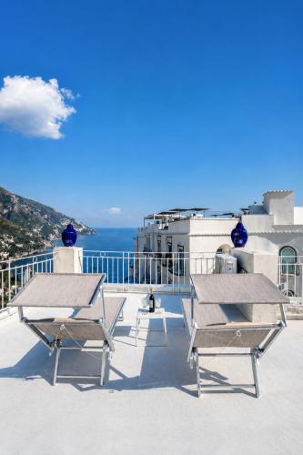 two picnic tables and chairs on the roof of a building at Love in Blue - La Terrazza di Positano in Positano