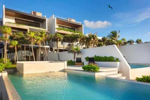 a swimming pool in front of a building with palm trees at Oceanview villa 4BR Concierge Service in Tulum