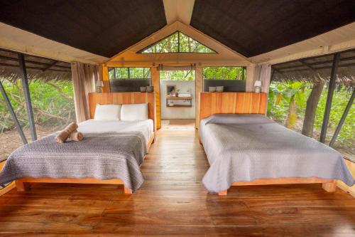 a bedroom with two beds in a room with windows at Four Monkeys Eco Lodge - Jungle & Beach in Cabo Matapalo