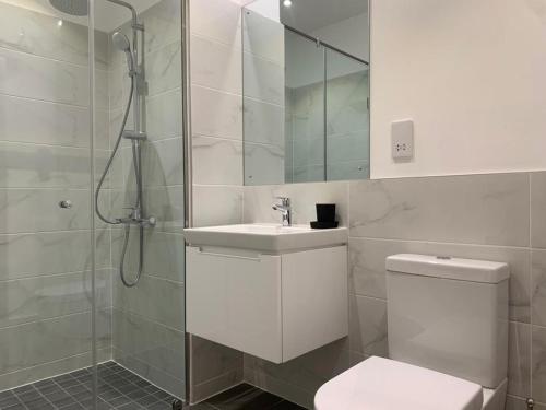 a bathroom with a shower and a toilet and a sink at The Snug Stay - Lennox in Accra