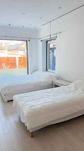 two beds in a white room with a window at Maison de Clare 메종드클레어 in Gyeongju