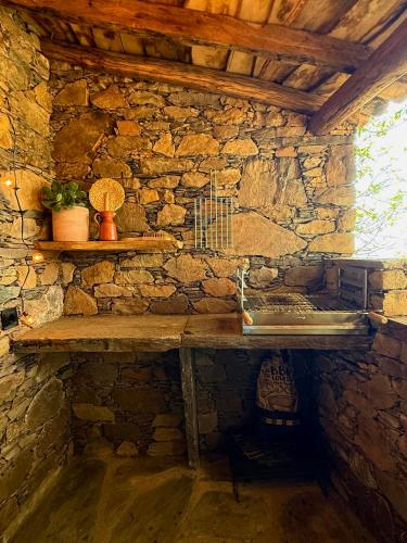 a stone bathroom with a sink and a stone wall at Casa do Ti Tóte in Talasnal