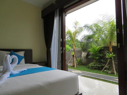a bedroom with a bed and a sliding glass door at Odah Ayu Guest House in Ubud