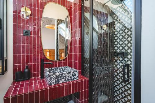 a red tiled bathroom with a sink and a mirror at La Maison dAmbre-Jacuzzi-Sauna-Clim-4chambres in Saumur