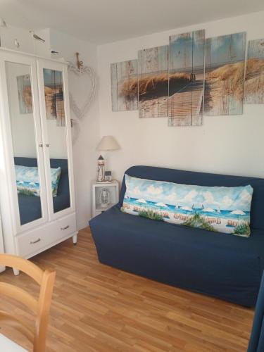 a living room with a blue couch and a window at Appartement Ste Cécile à 50 mètres de la plage in Sainte-Cécile-Plage