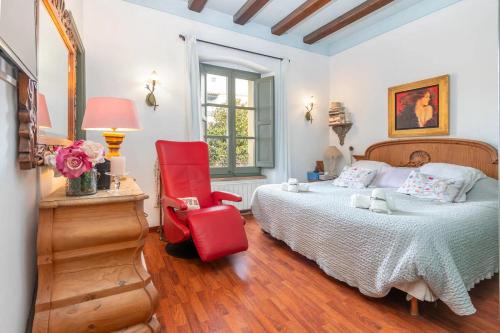 a bedroom with a bed and a red chair at Centro Palafrugell: Casa con Piscina y Solárium in Palafrugell
