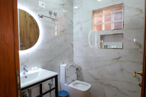 a white bathroom with a toilet and a sink at Fabiani Boutique Hotel Castle Gate in Krujë