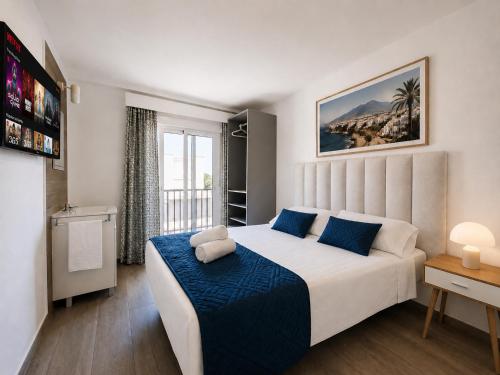 a bedroom with a large white bed with blue pillows at Sun Serramar Boutique Hostal in Benalmádena