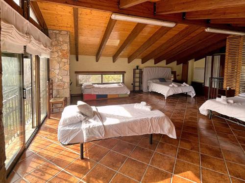 a room with three beds in a room with wooden ceilings at Masía de piedra con piscina in Riudecols