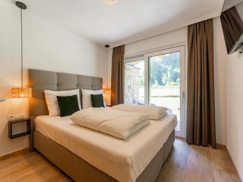 a bedroom with a large bed with a large window at FIIF Pinzgau in Wald im Pinzgau