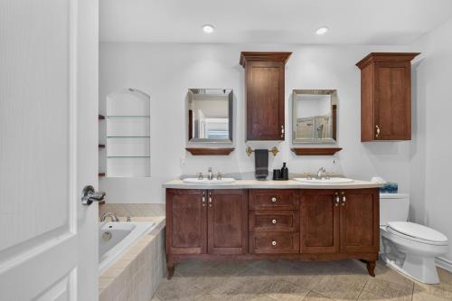 a bathroom with two sinks and a tub and a toilet at Private Waterfront Villa 9 BR Peaceful in Laval