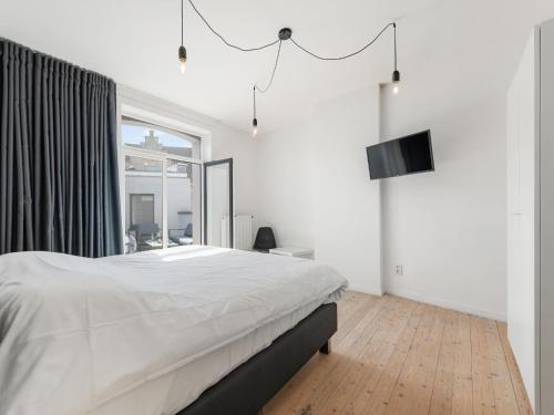 a white bedroom with a bed and a television at t Loftje in Veurne