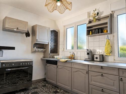 a kitchen with white cabinets and a black stove at Duplex 2 à 4p. tout confort in Dolleren