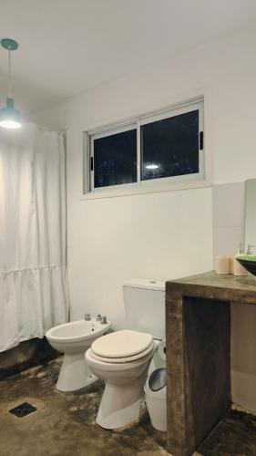 a white bathroom with a toilet and a sink at Casa Aguaribay- Lomas Altas- in Chascomús