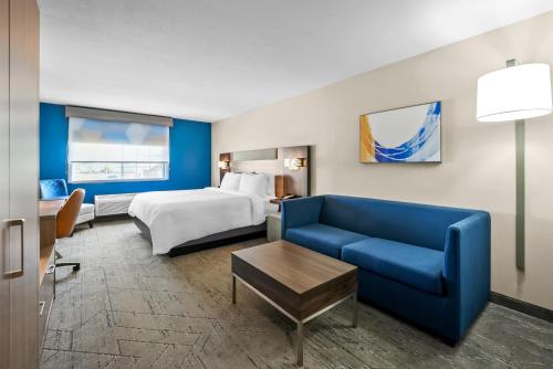 a hotel room with a bed and a blue couch at Holiday Inn Express Hotel & Suites Wabash by IHG in Wabash