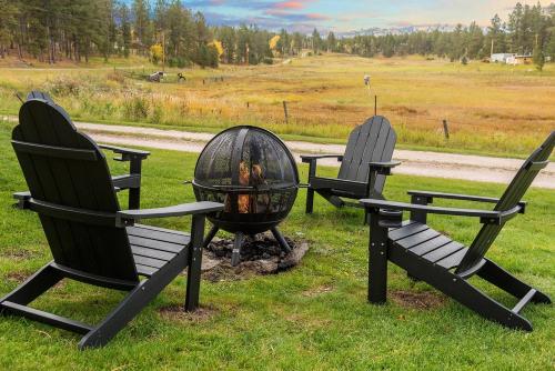 three chairs and a fire pit in the grass at Hobbit Hole BHBungalows #3 in Custer