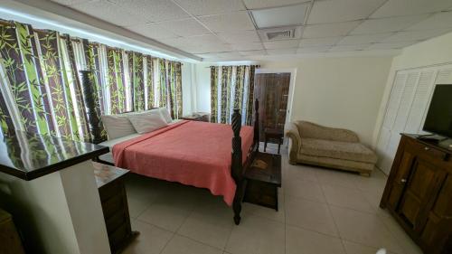 a bedroom with a bed with a red blanket and a chair at The Crown House Hotel in Philipsburg