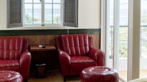 two red chairs and a table in a room with windows at Auberge Bonne Chere Raout in Onna