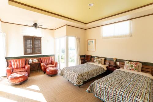 a bedroom with two beds and a chair at Auberge Bonne Chere Raout in Onna