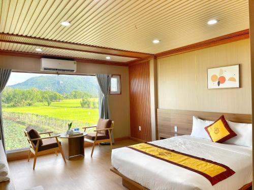 a bedroom with a bed and a large window at Rồng Vàng Resort in Tri Tôn