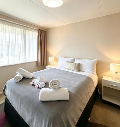 a bedroom with a large bed with towels on it at Cosy on Goldfinch in Ohakune