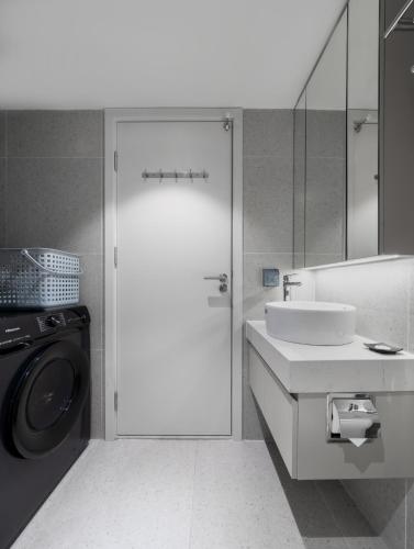 a white bathroom with a sink and a washing machine at Little Charm Boutique Hotel in Hanoi