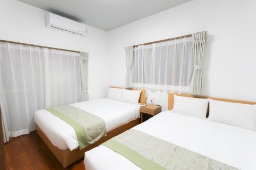 two beds in a room with white walls and windows at Danran HAKATA in Fukuoka