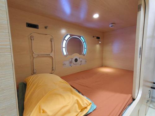 a small room with a bed and a mirror at Sleepy Bear Capsule Hostel in Johor Bahru