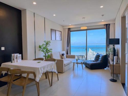a living room with a table and chairs and the ocean at The Song Vung Tau - Infinity Pool & Sea View - Căn Hộ Du Lịch Tháp Tam Thắng - HOUSES BY THE SEA in Vung Tau
