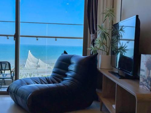 a living room with a blue couch and a tv at The Song Vung Tau - Infinity Pool & Sea View - Căn Hộ Du Lịch Tháp Tam Thắng - HOUSES BY THE SEA in Vung Tau