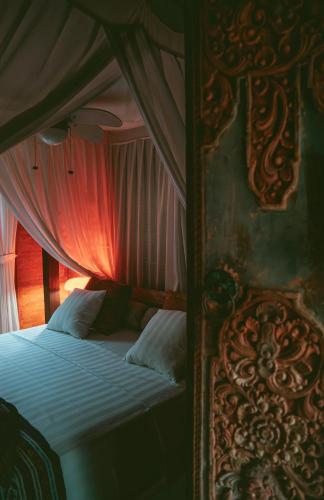a bedroom with a bed with a red curtain at HIDDEN HEAVEN Rumah Barong in Jasri